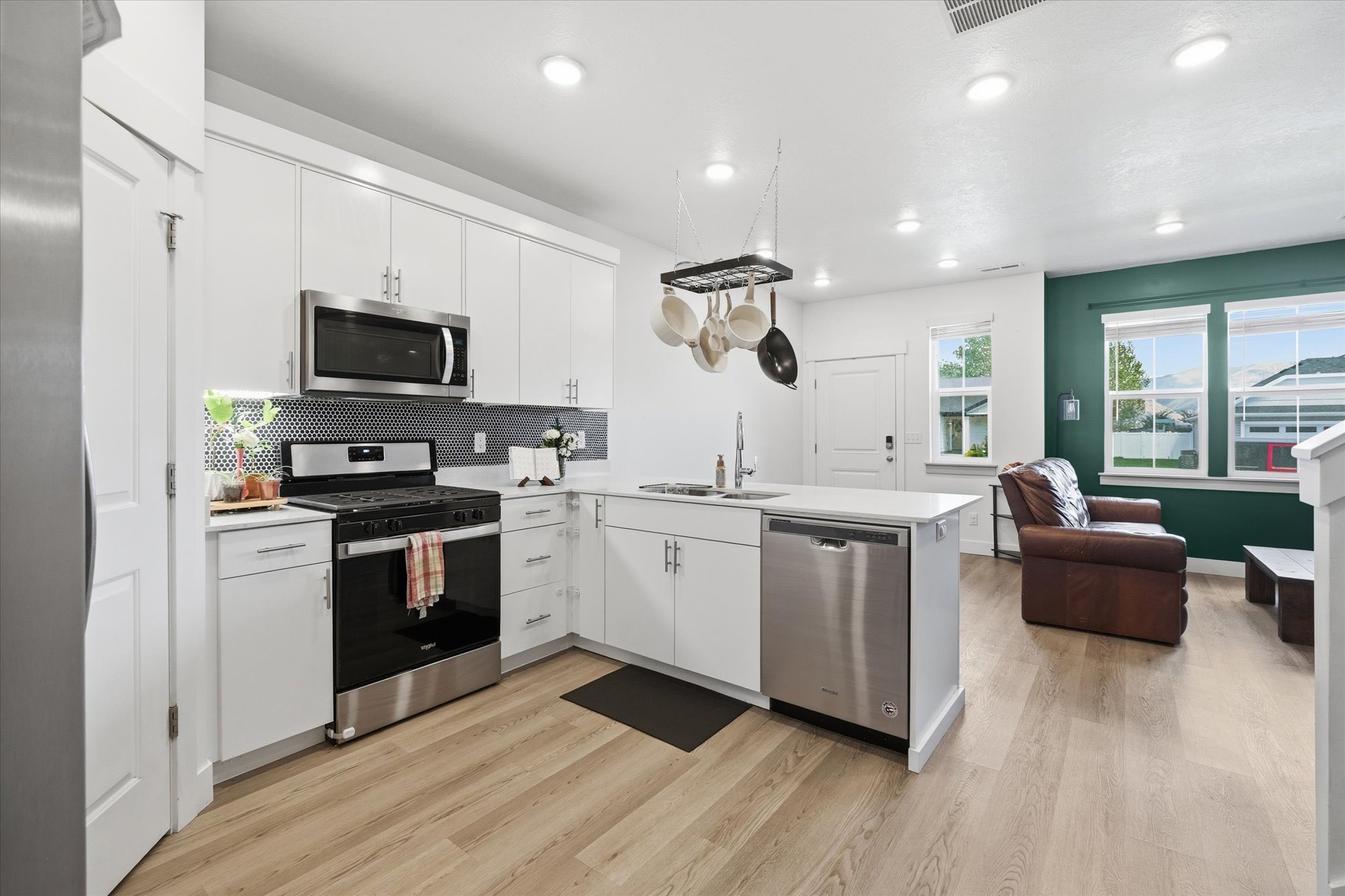 Modern kitchen featuring white cabinetry, light countertops, stainless steel appliances, and a black patterned backsplash