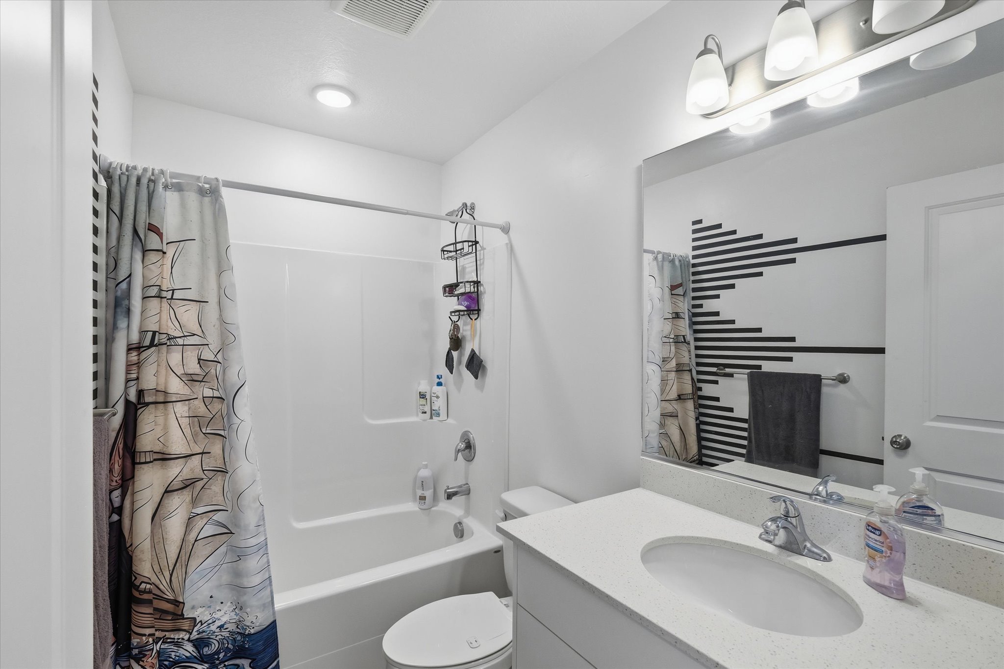 Bathroom featuring a white vanity with a light-colored countertop, an oval undermount sink, and a chrome faucet