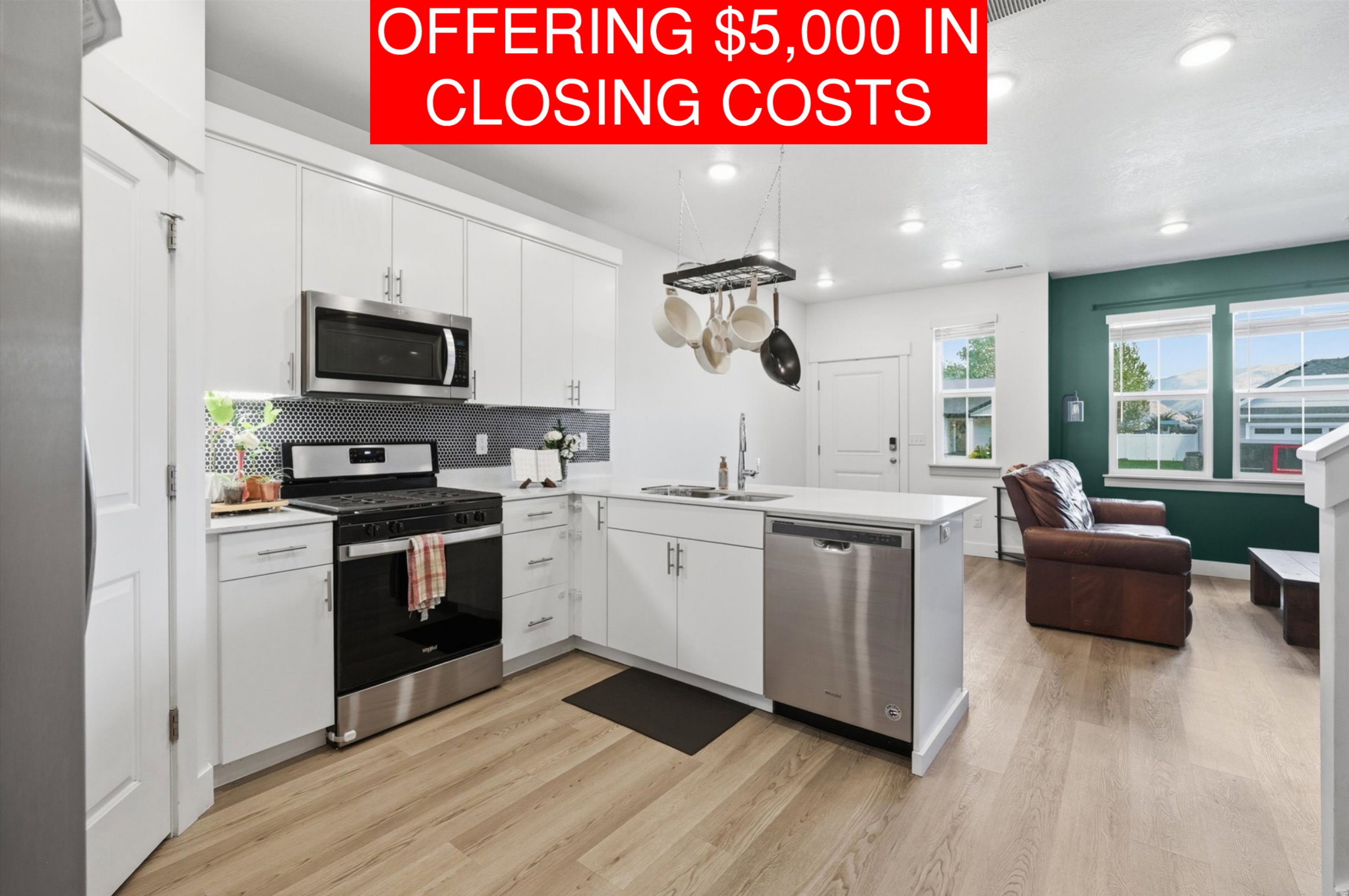 Open-concept kitchen featuring white cabinetry, stainless steel appliances, and wood-finish flooring