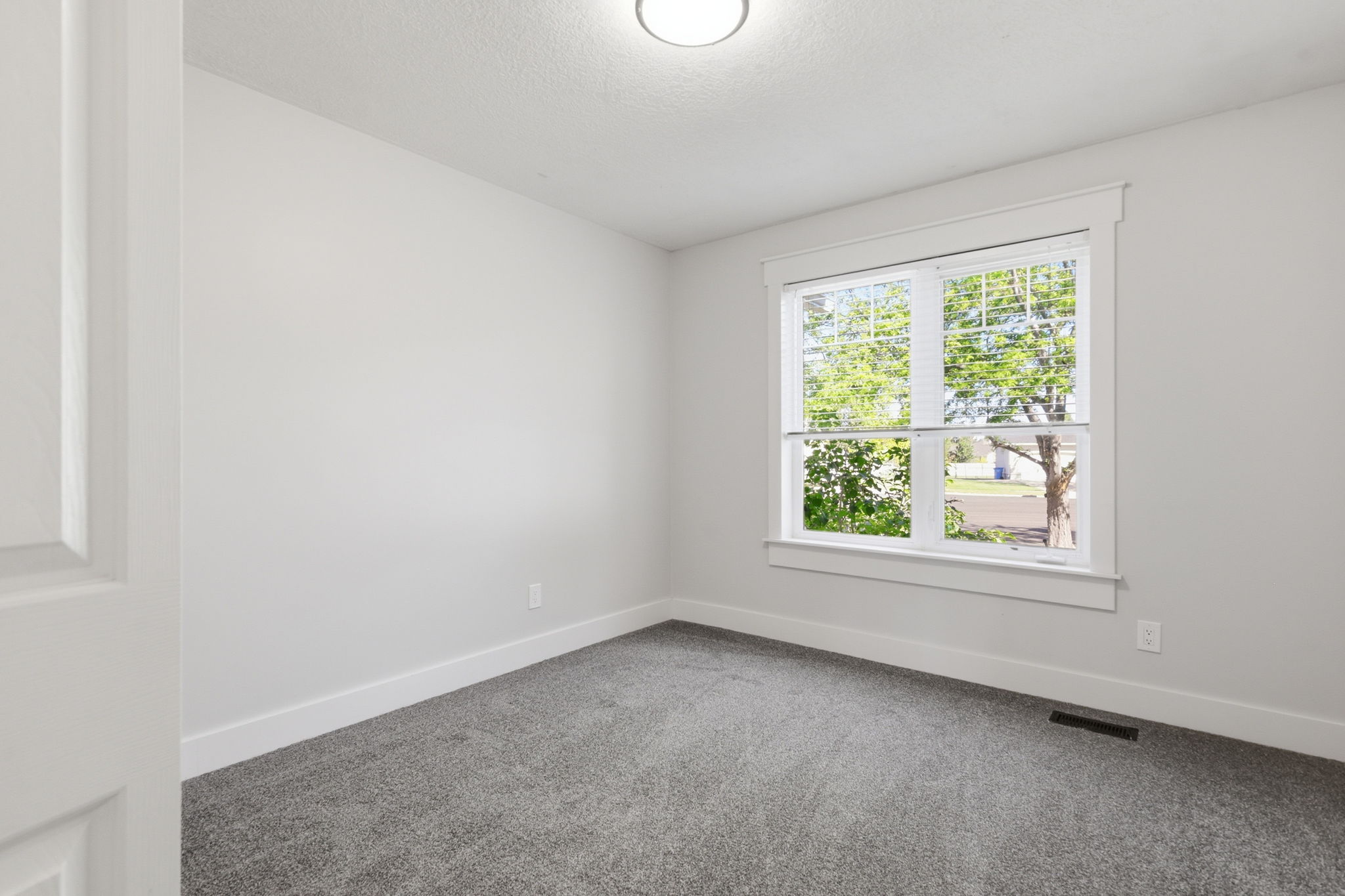 Room featuring light gray walls, gray carpet flooring, and white baseboards