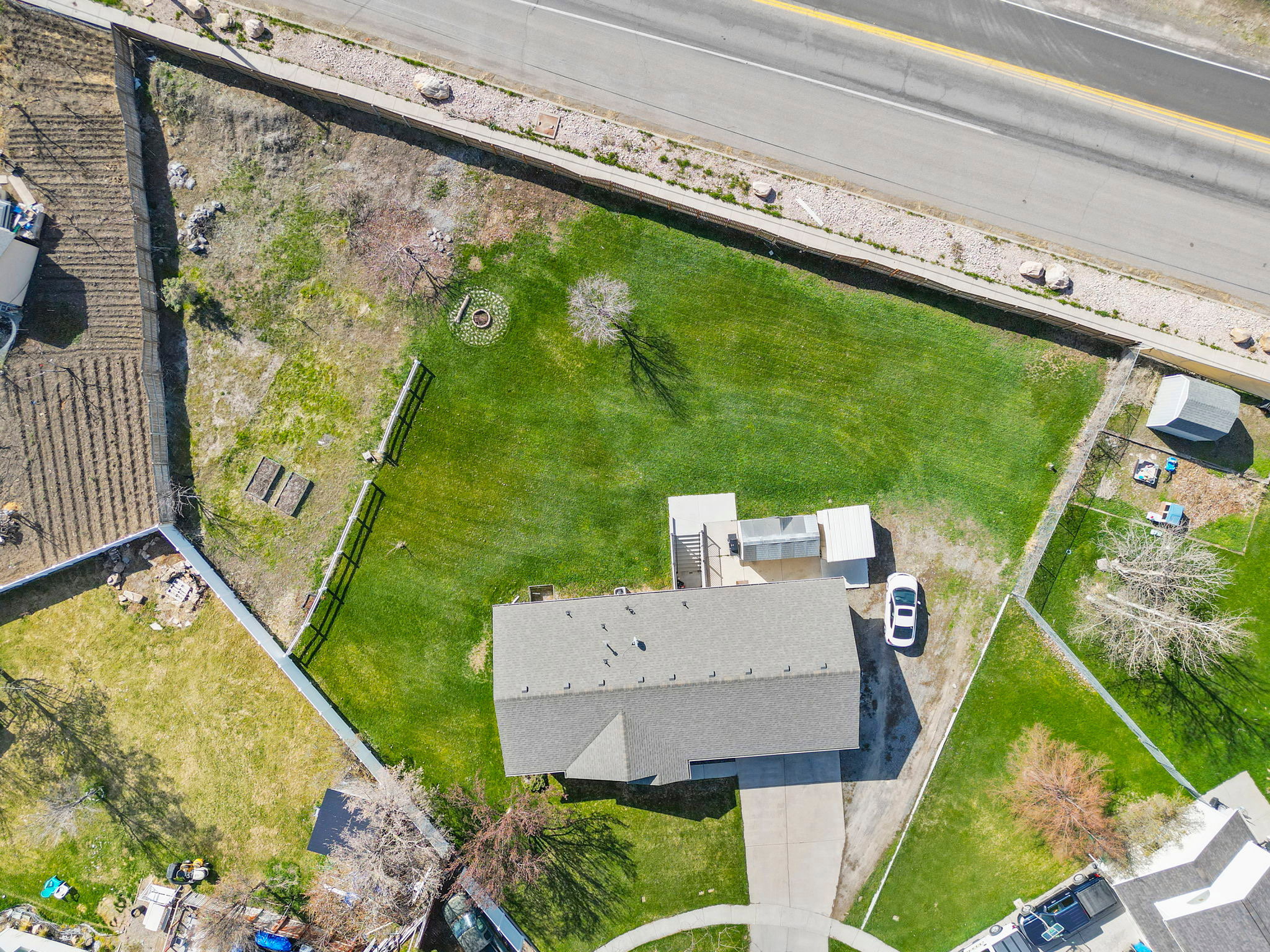 Generous lot featuring a large lawn area, mature trees, and a gravel driveway