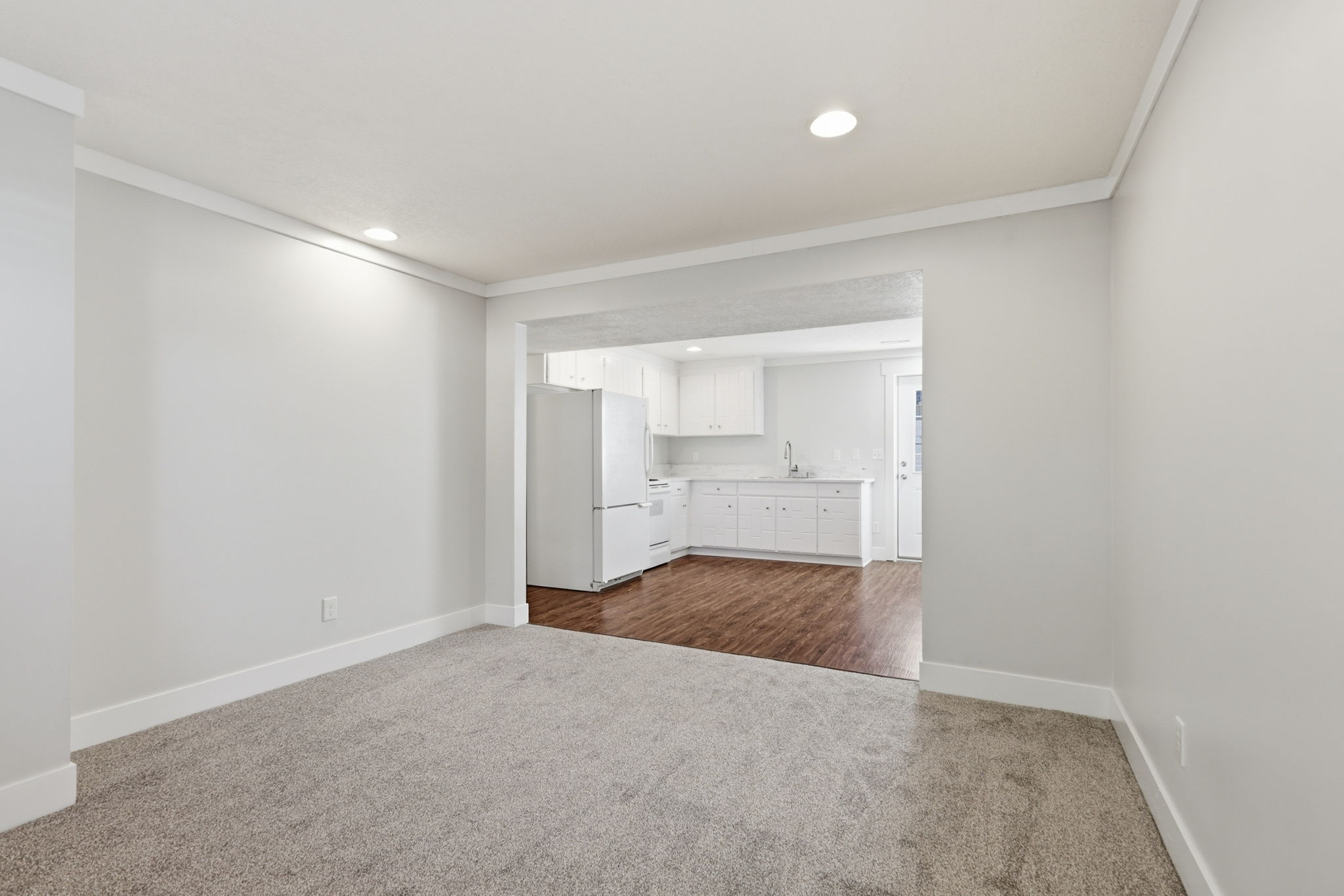 Open concept living space featuring neutral gray carpeting and white crown molding