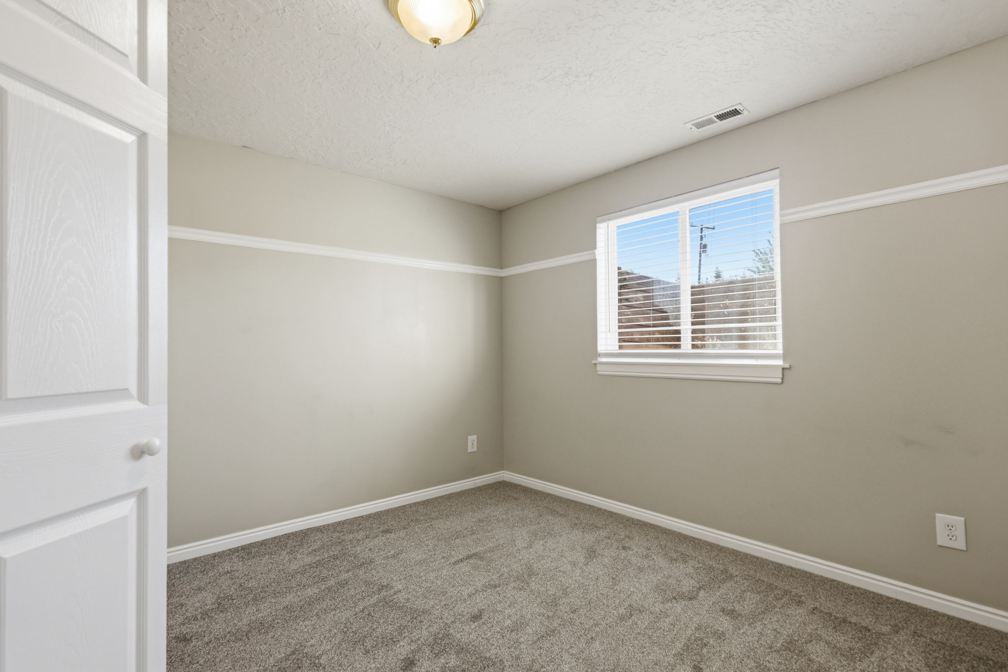 Neutral-toned interior room with gray carpet flooring and white baseboards