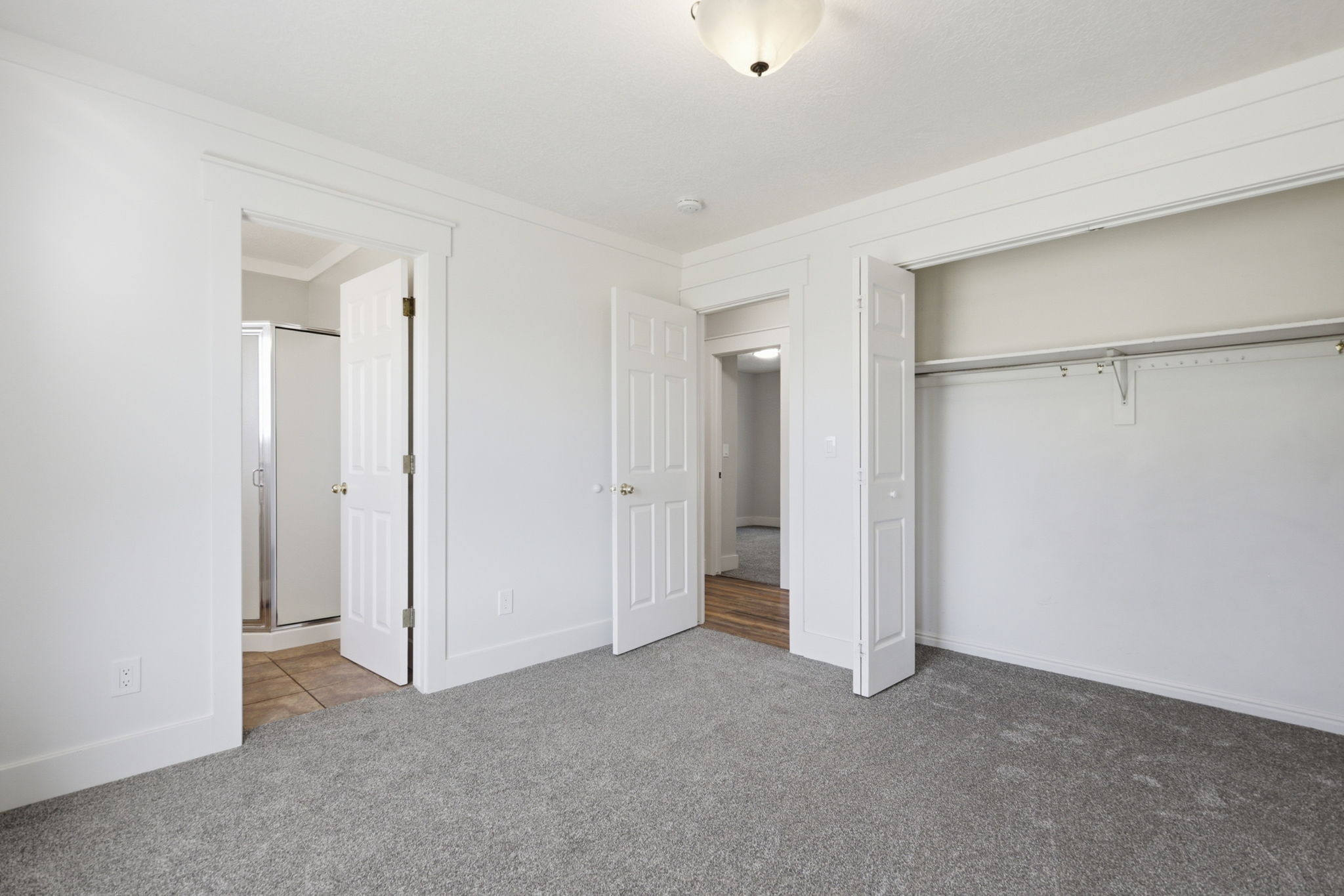Spacious room featuring gray carpeting, white trim, and a semi-flush mount ceiling light