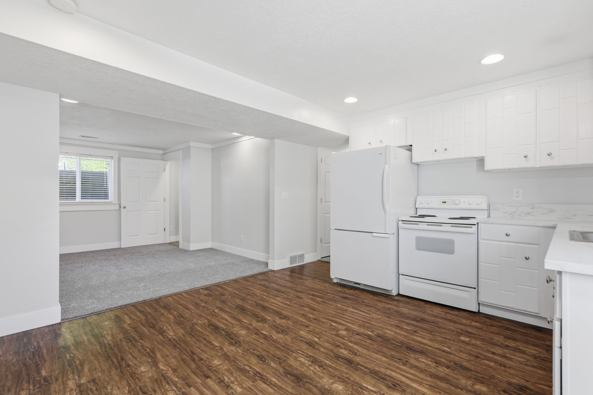 Kitchenette featuring white cabinetry with silver hardware, an electric range, a refrigerator, and white countertops with an integrated sink