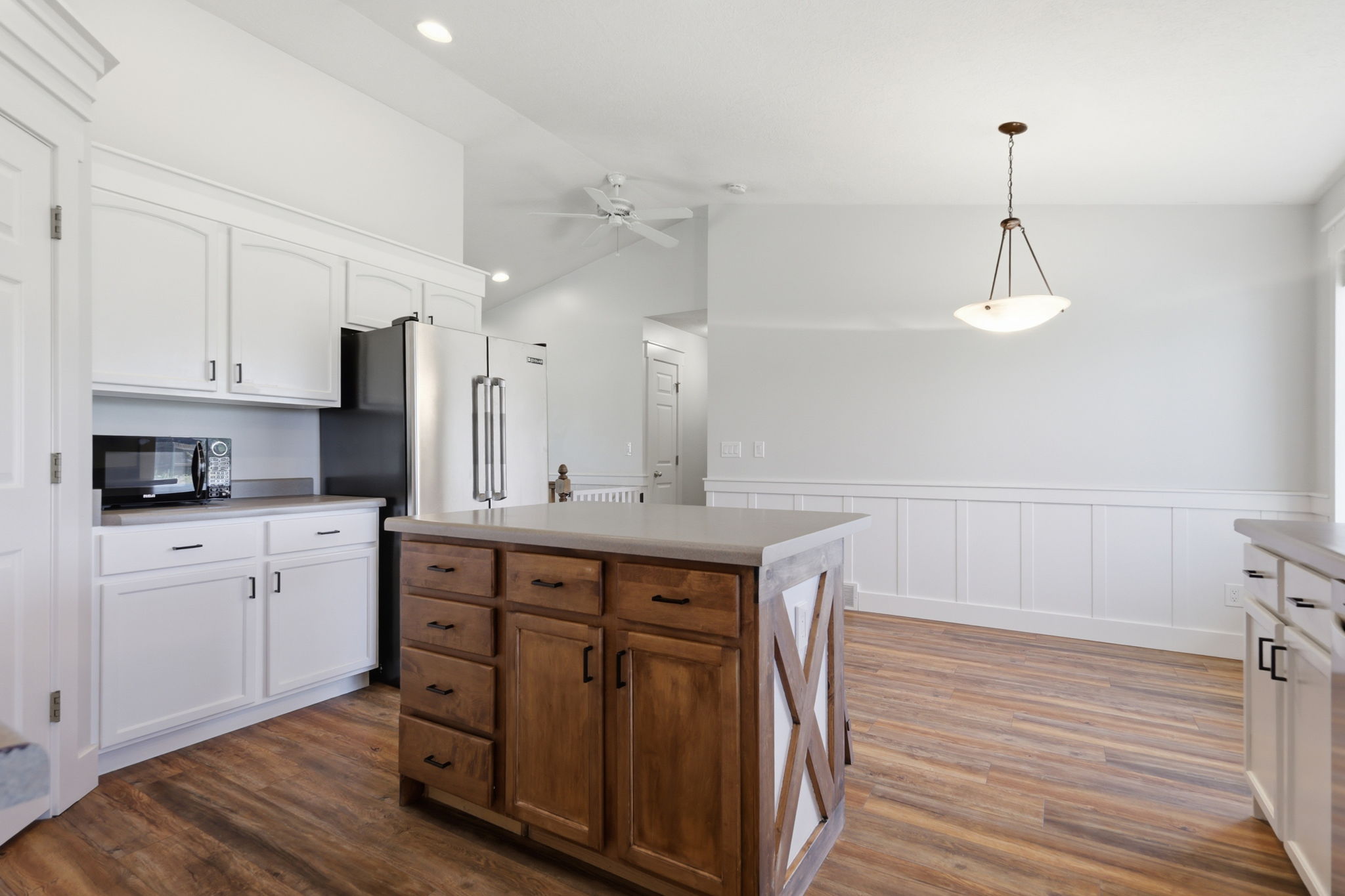 Kitchen featuring white cabinetry, wood-finish flooring, and a central island with wood cabinetry and a light-toned countertop