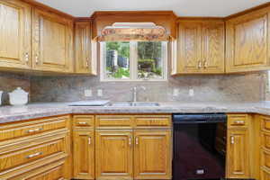 Kitchen featuring extensive wood cabinetry, coordinating stone countertops, a stainless steel double basin sink, and a black built-in dishwasher