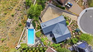 Modern metal roof residence featuring a rectangular swimming pool, terraced landscaping, and an attached paver driveway