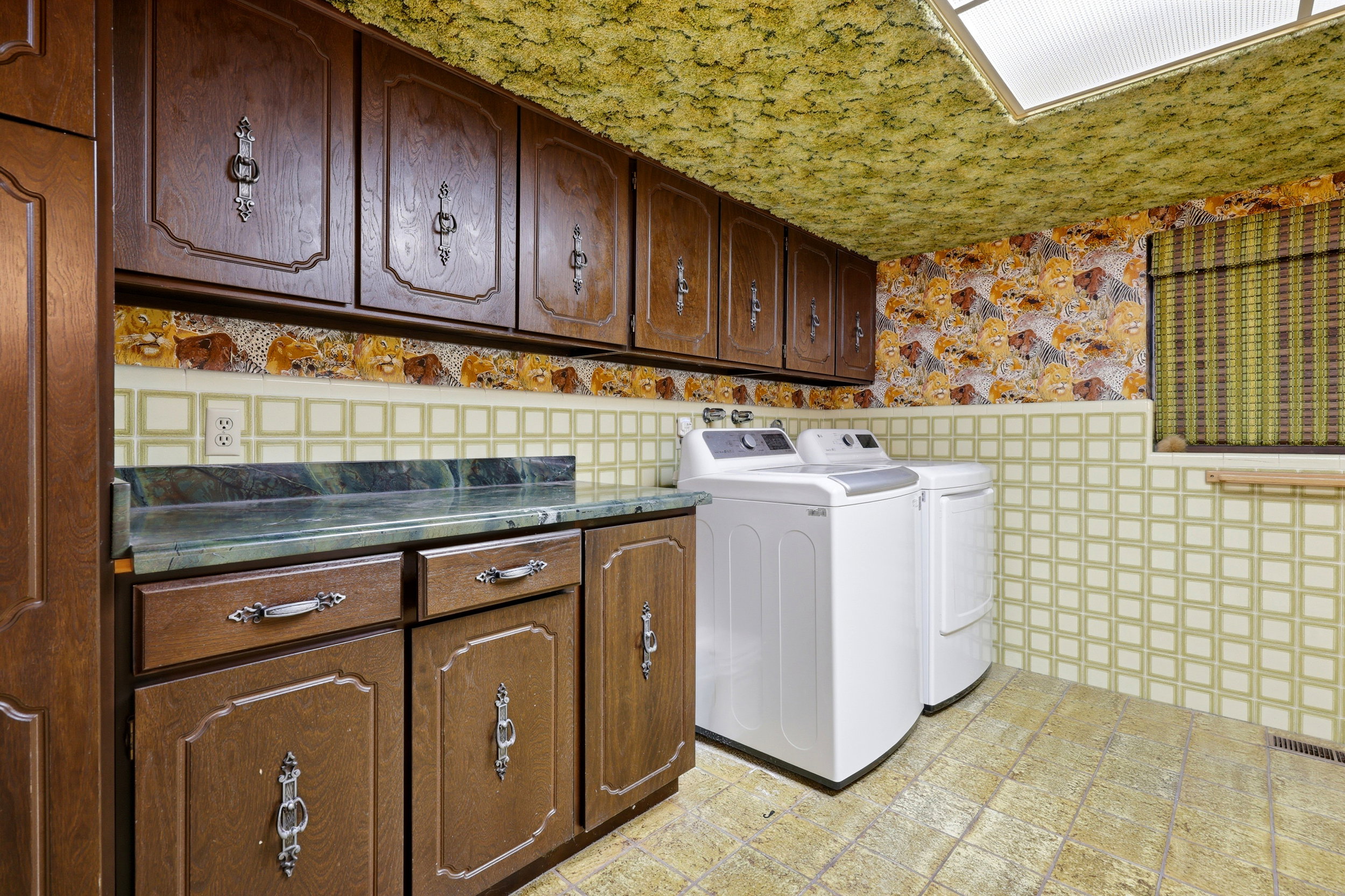 Laundry space featuring extensive wood cabinetry, a green countertop, and square pattern wall tiling