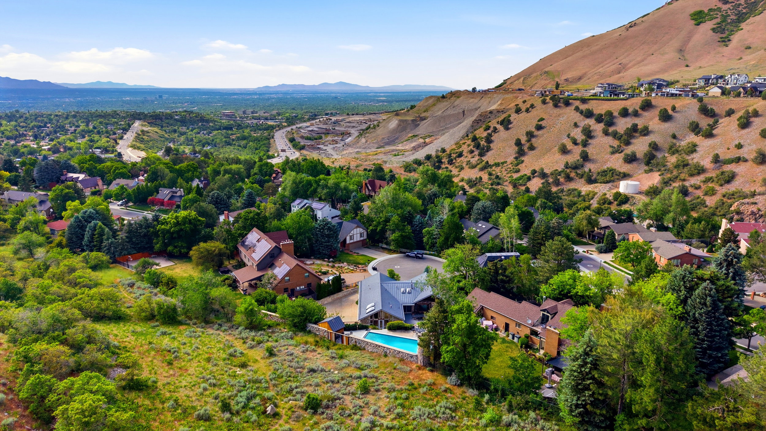 Expansive property featuring a contemporary residence with a private swimming pool, mature trees, and mountainous terrain