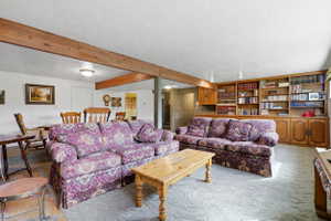Wood-finish ceiling beams, built-in shelving, recessed and surface-mounted lighting, and neutral wall paint
