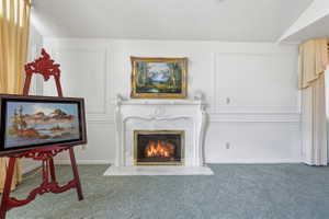 Ornate fireplace with a marble surround and hearth, framed by white paneled walls and light-colored drapes