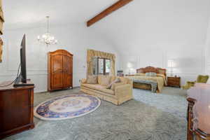 Spacious room featuring vaulted ceilings with exposed wood beams, wall molding, and a decorative chandelier