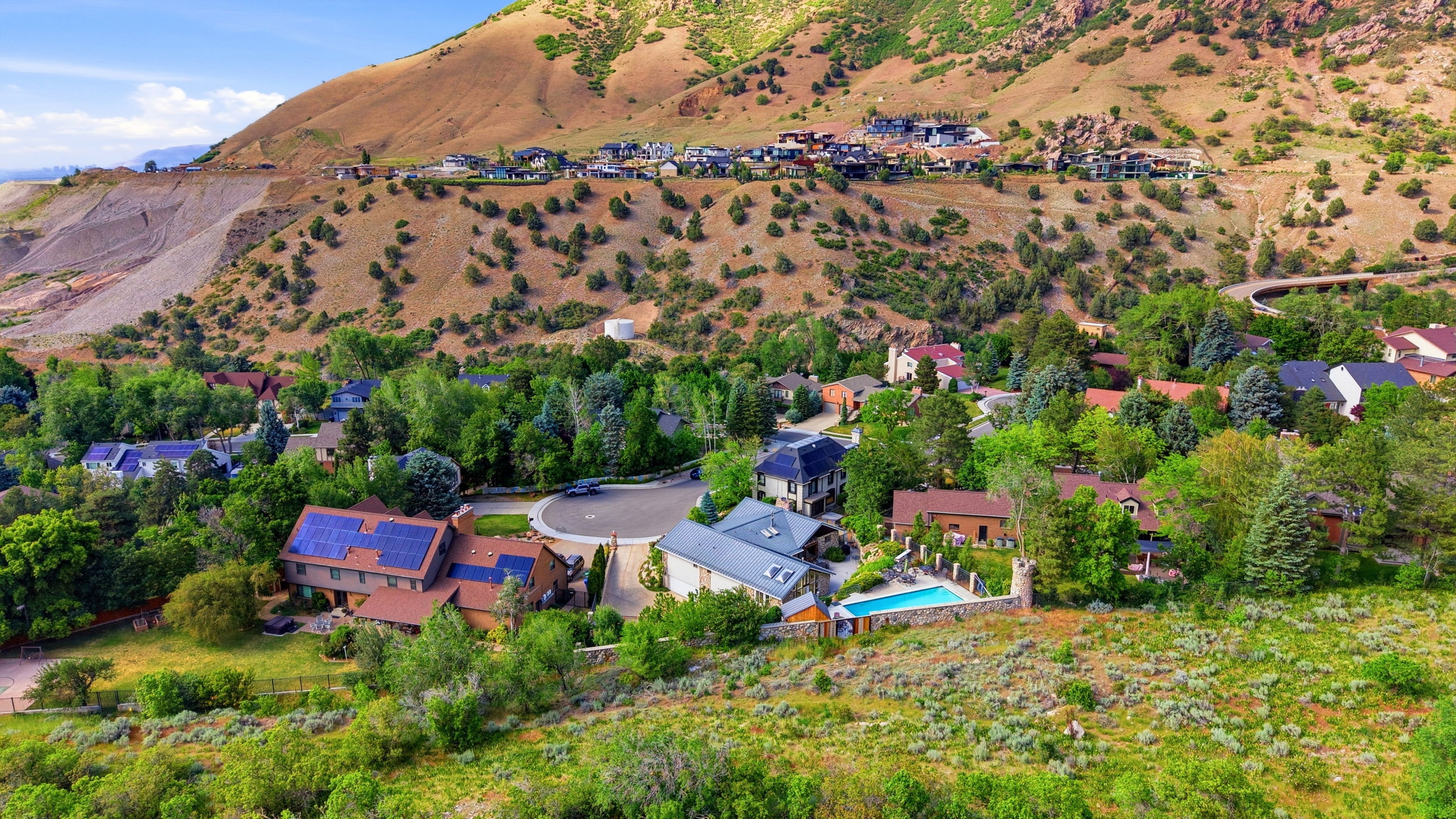 Residential community nestled against a mountainous backdrop with dense tree coverage