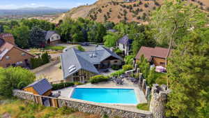 Expansive outdoor living area featuring a rectangular swimming pool, stone retaining walls, and a dedicated pool house