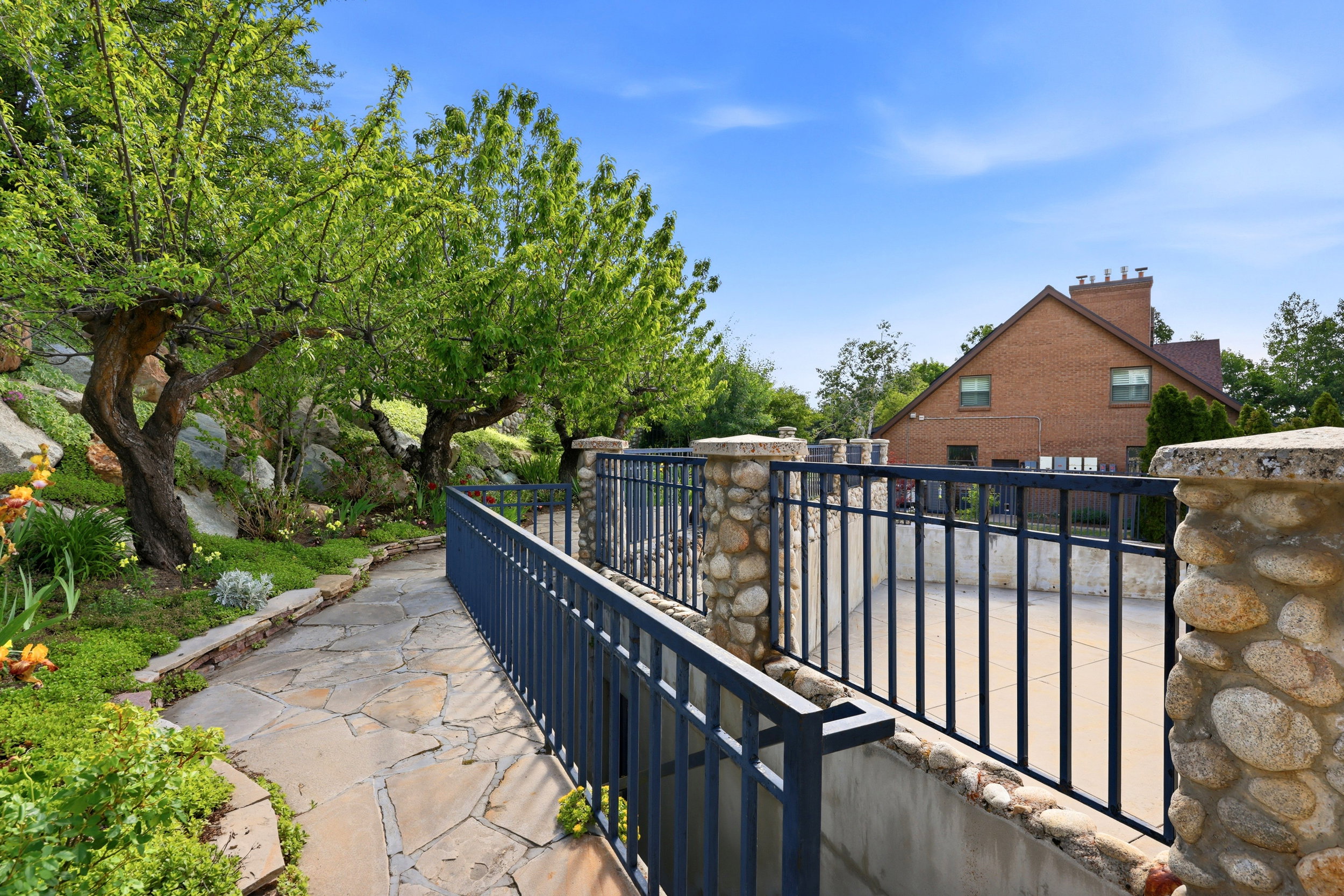 Stone pathway bordered by lush greenery and mature trees