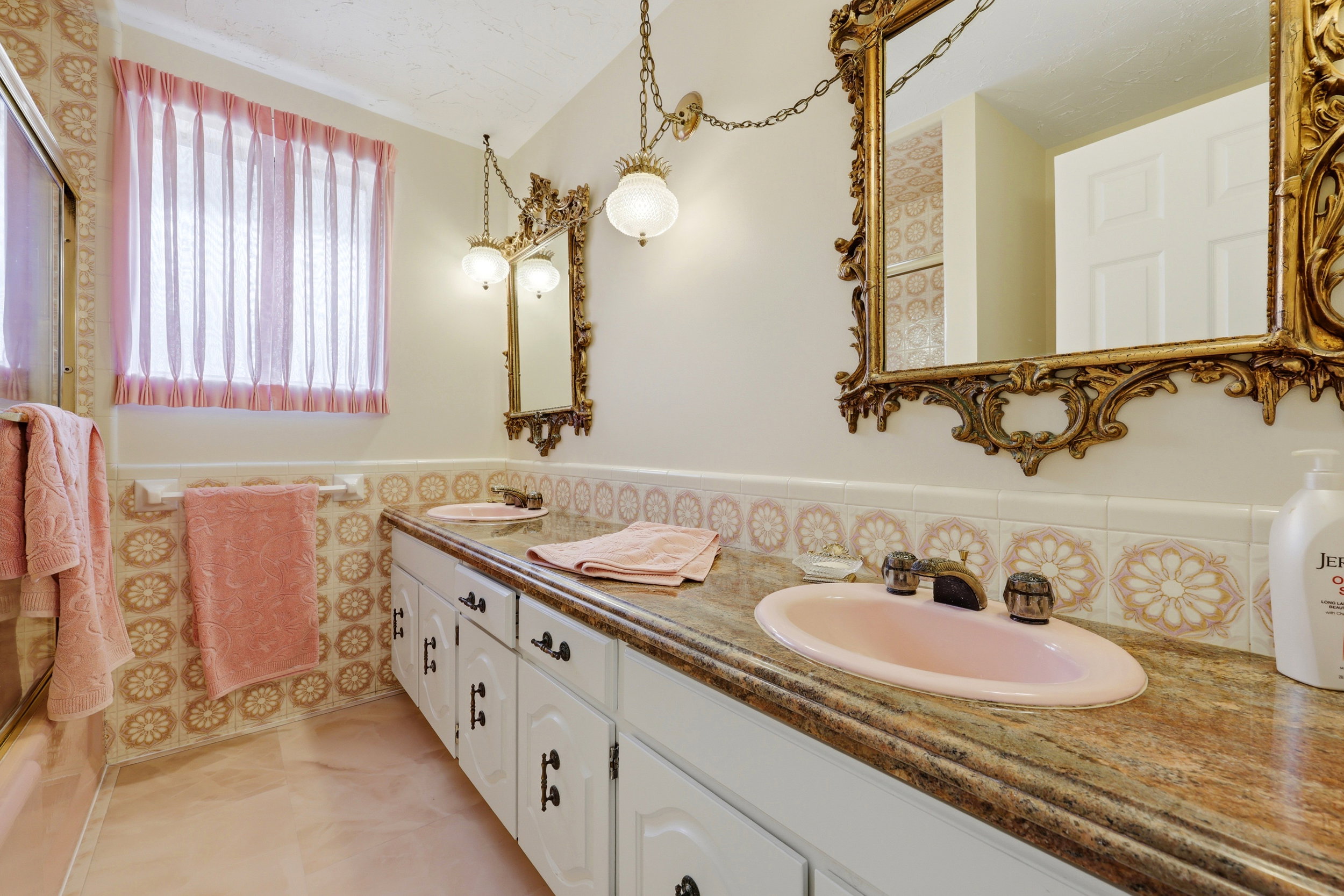 Dual vanity with integrated pink sinks and coordinating patterned tile backsplash