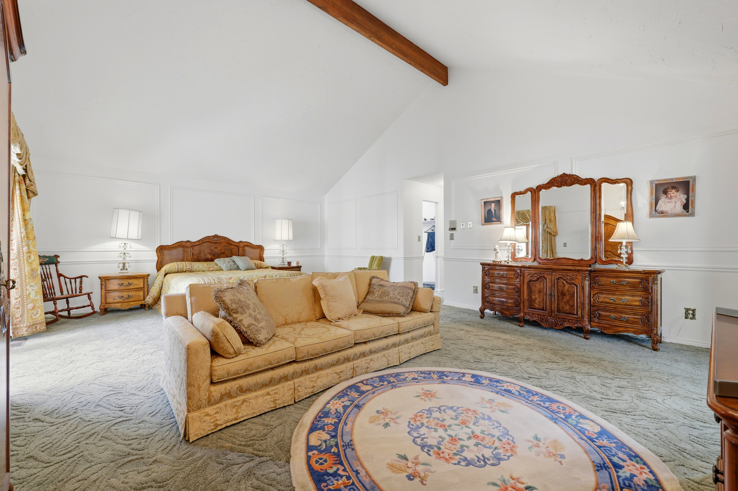 Spacious room featuring vaulted ceilings with an exposed beam, white wall paneling, and an alcove with a built-in closet