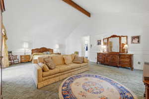 Spacious room featuring vaulted ceilings with an exposed beam, white wall paneling, and an alcove with a built-in closet