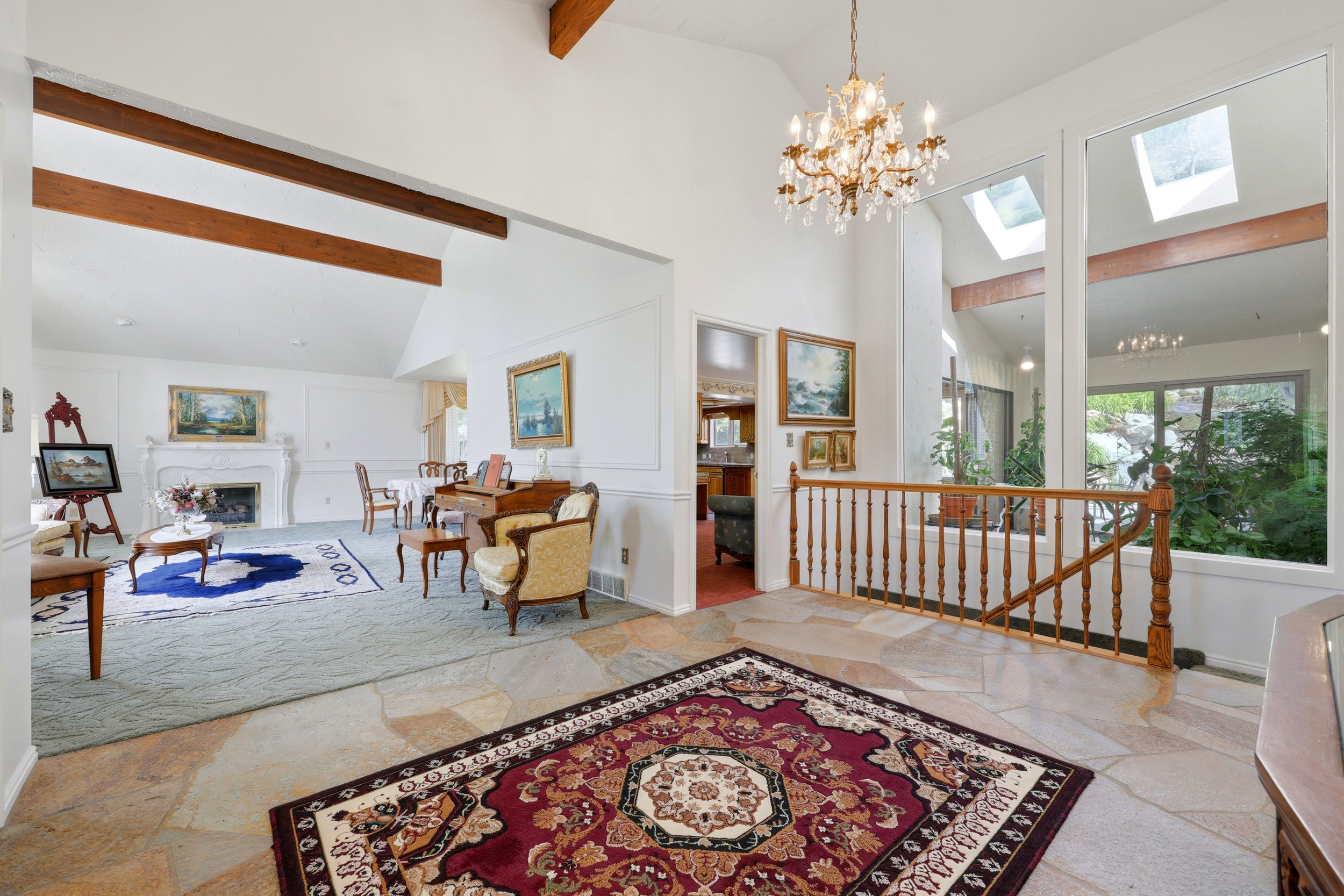 Foyer featuring natural stone flooring, a decorative chandelier, and a wood banister