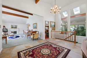 Foyer featuring natural stone flooring, a decorative chandelier, and a wood banister