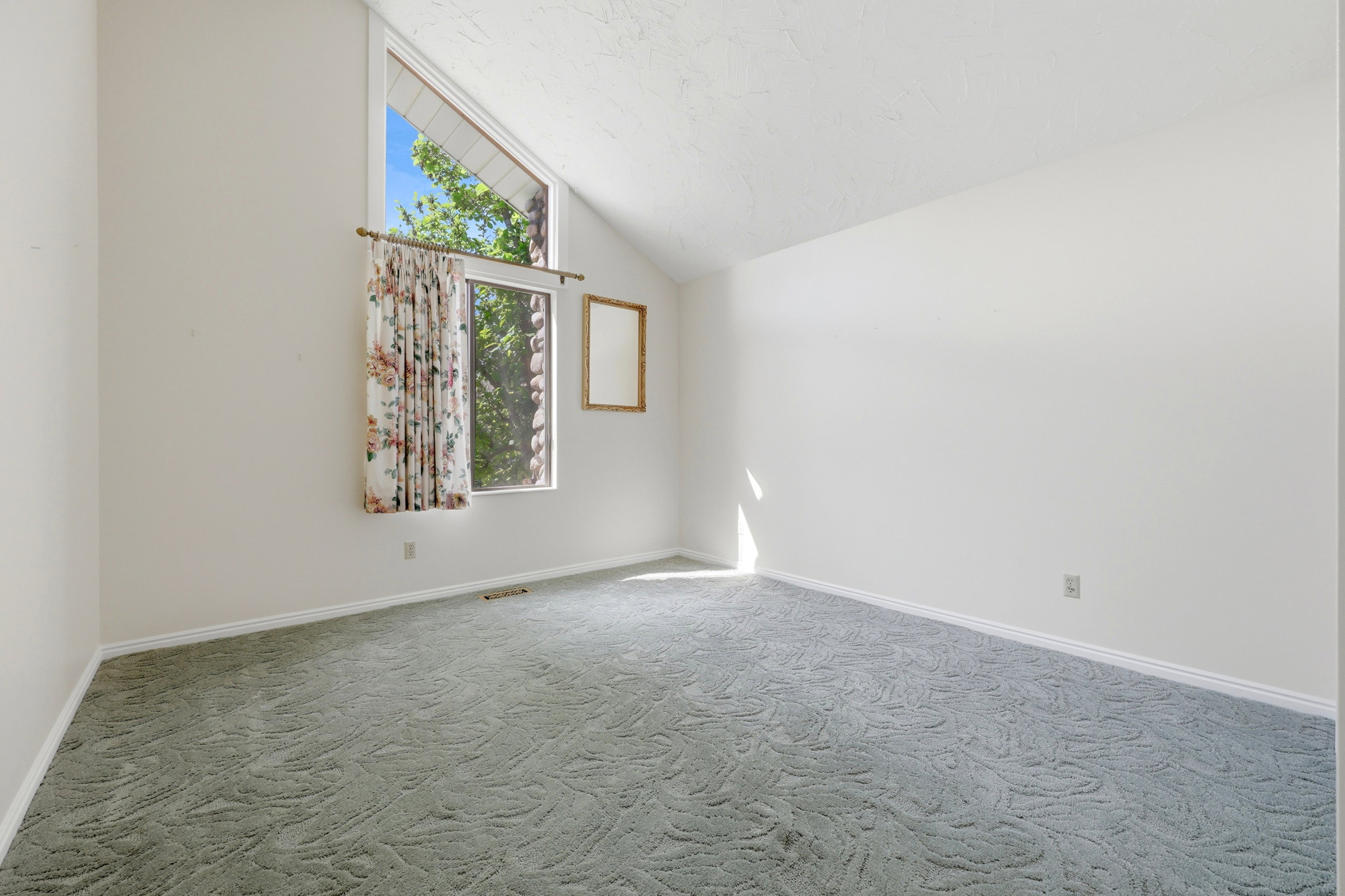 Room featuring a vaulted ceiling and an expansive window with additional transom pane