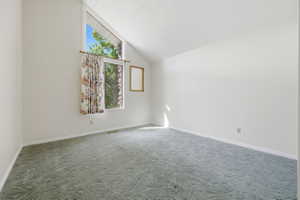 Room featuring a vaulted ceiling and an expansive window with additional transom pane