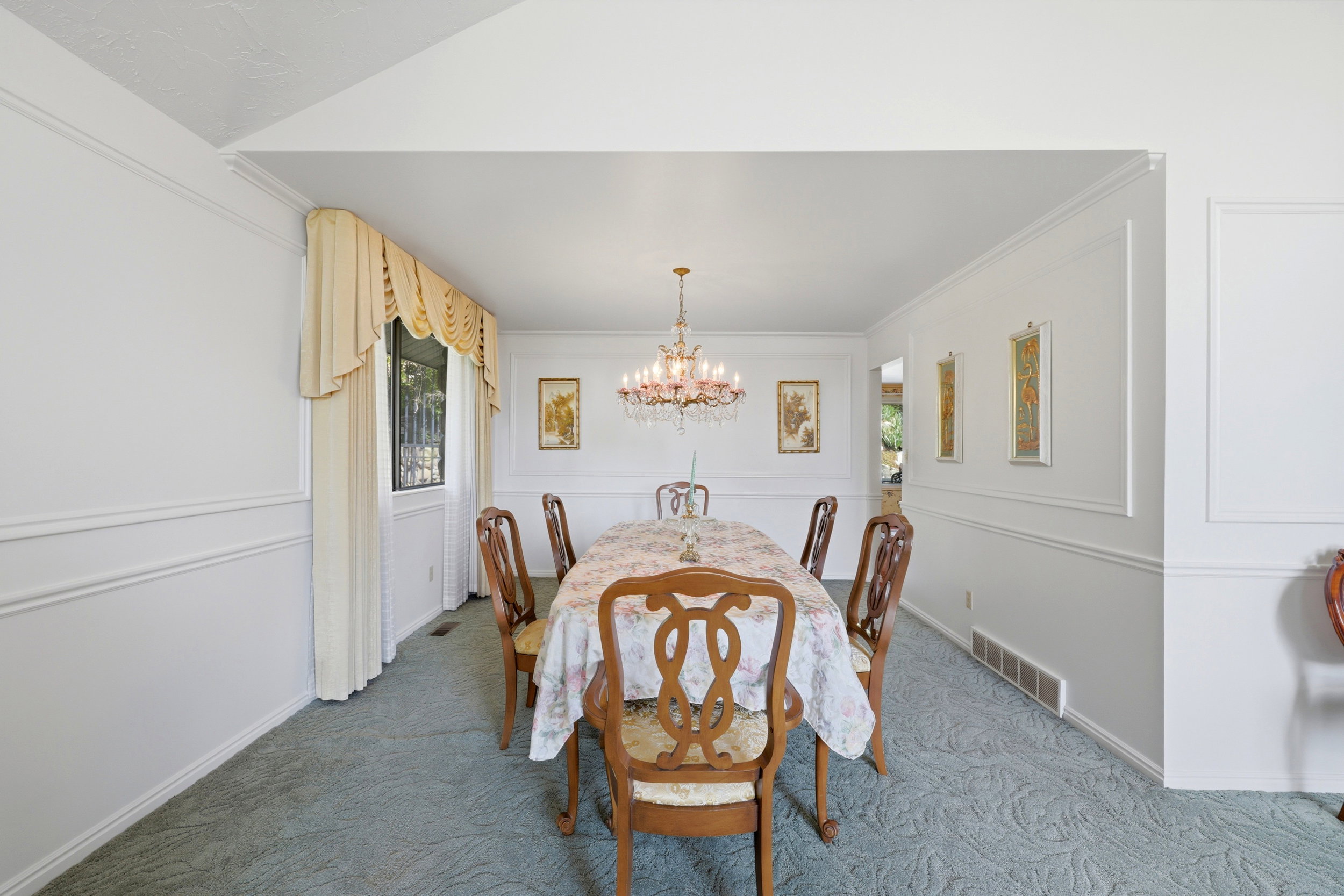 Dining area featuring a chandelier, wall molding, neutral-toned curtains, and blue patterned carpeting