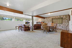 Spacious room featuring light-colored carpet flooring, a stone accent wall, and multiple windows