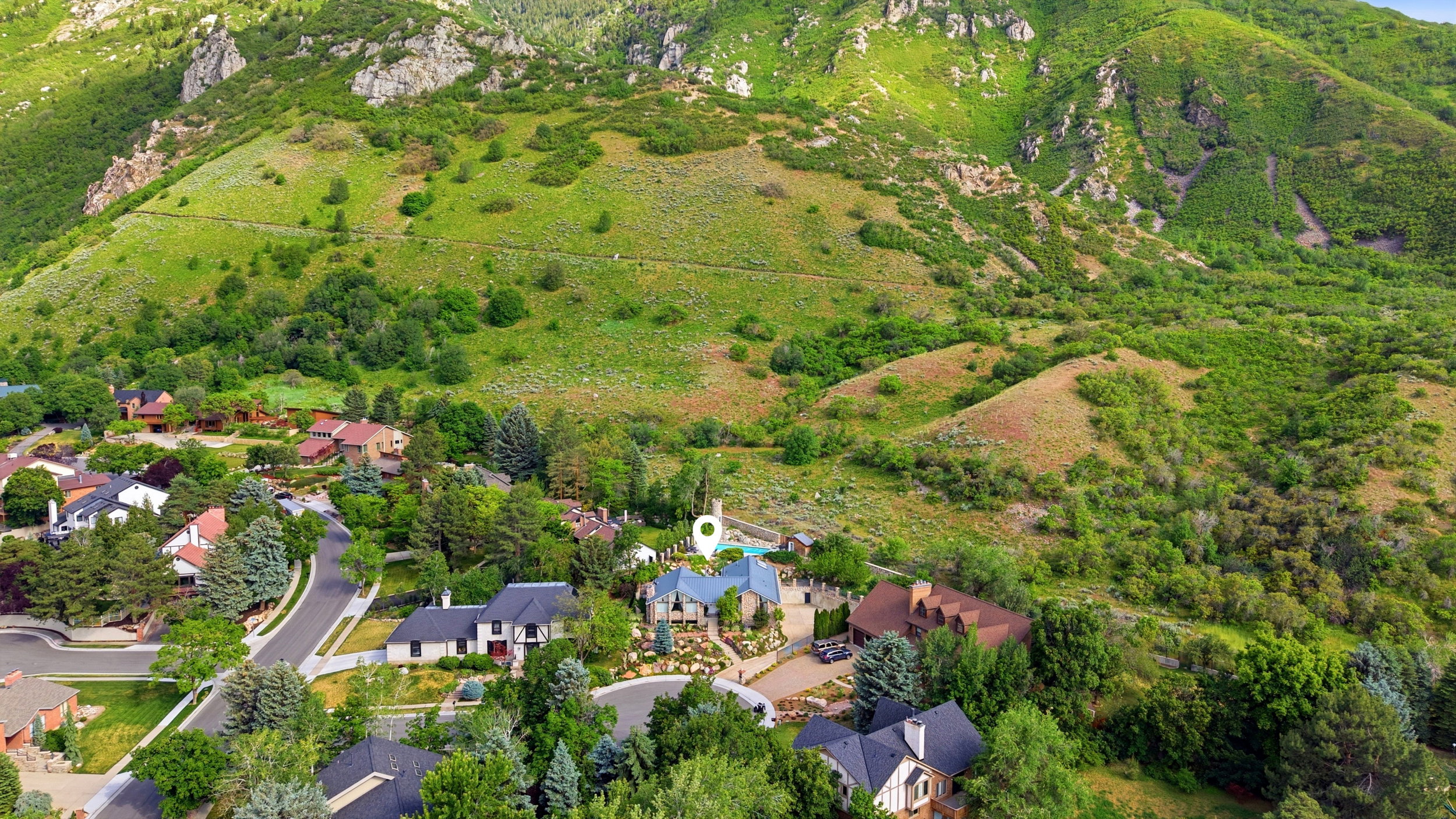 Hillside property featuring a multi-level residence with a blue-tiled roof and extensive landscaping