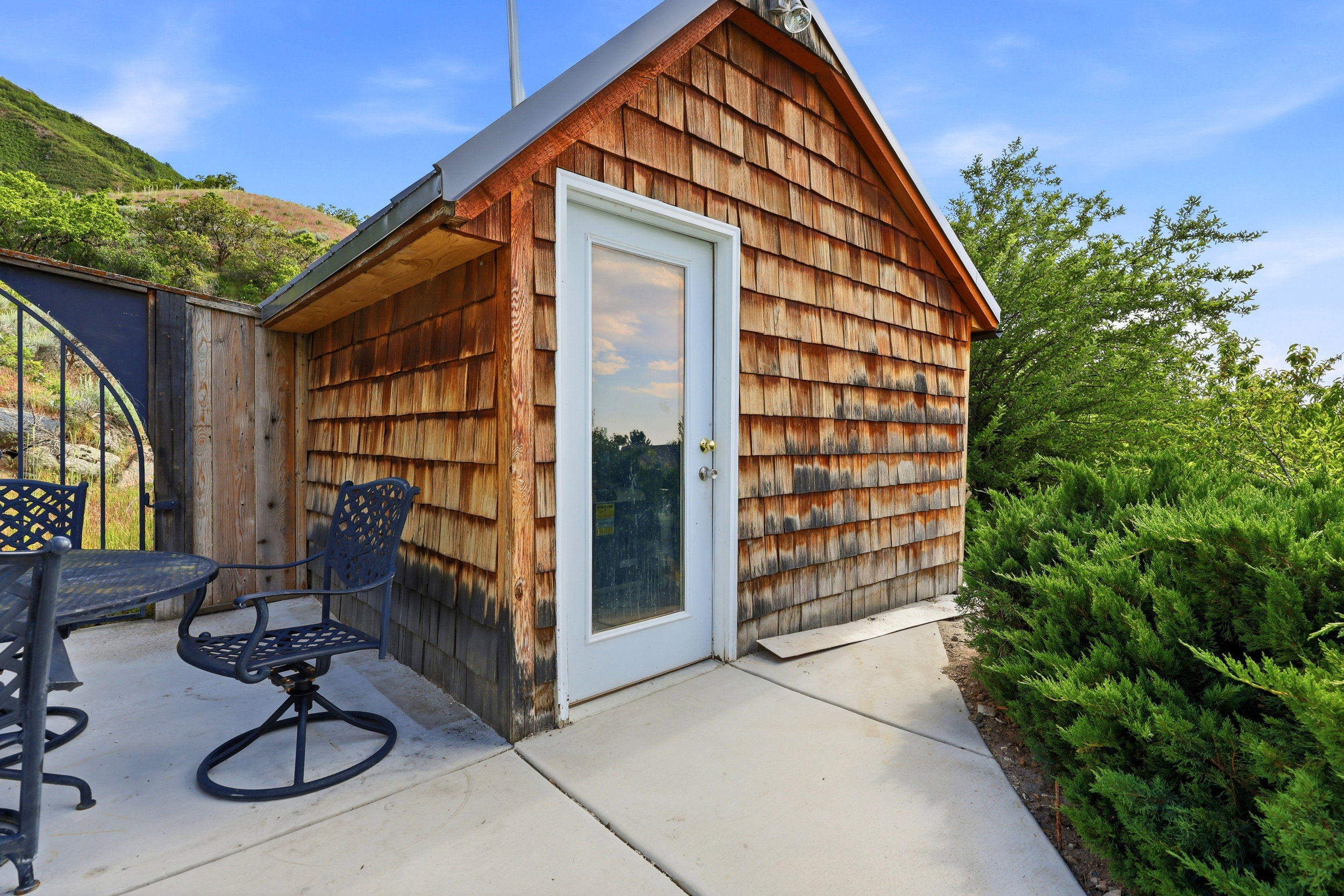 Cedar shake siding structure with a white-framed glass paneled door and metal roof