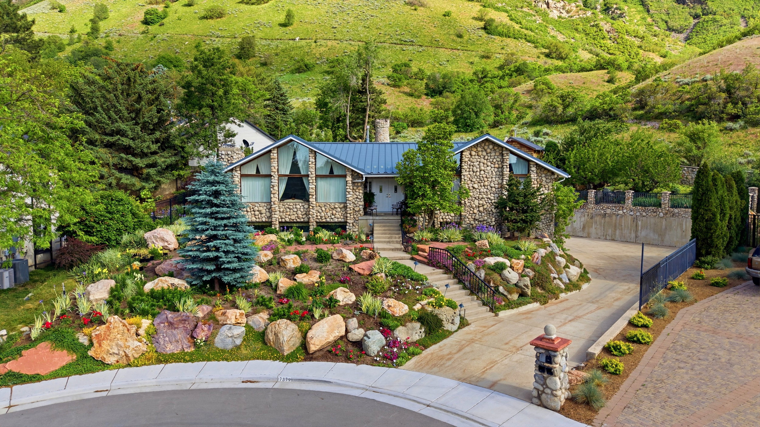 Stone-clad residence featuring a blue metal roof and large A-frame windows