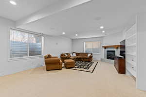 Spacious room featuring carpet flooring, recessed lighting, and a corner fireplace with a tile surround and wood mantel
