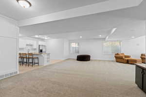 Spacious open-concept lower level featuring plush carpeting, recessed lighting, and multiple windows with blinds