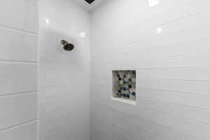 Shower featuring subway tile walls, a built-in niche with hexagonal accent tile, and a bronze showerhead