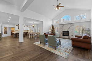 Spacious living area featuring high vaulted ceilings, expansive wood-finish flooring, and a marble-clad fireplace with a dark insert