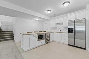 Lower-level kitchen featuring white cabinetry, granite-finish countertops, subway tile backsplash, and stainless steel appliances