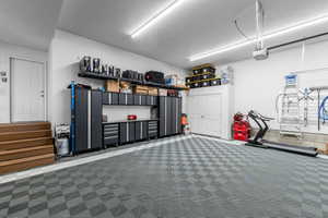 Garage space featuring checkerboard pattern flooring, extensive built-in cabinetry, and overhead storage solutions