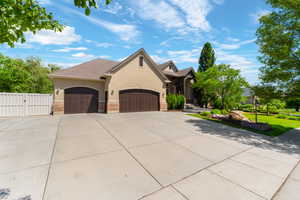Stucco exterior with brick accents, featuring a multi-car driveway, two arched garage doors, a decorative entry, and a side access gate
