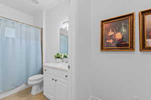 Bathroom featuring a tiled shower surround, a white vanity with an integrated sink, a mirrored wall, and a toilet