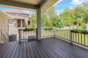 Spacious covered deck featuring dark wood-finish flooring, light-colored railings, and ceiling fan fixture