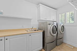 Laundry area with upper and lower white cabinetry, a utility sink, and a light-toned countertop