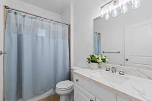 Bathroom featuring a single vanity with a white countertop and integrated sink, chrome fixtures, and overhead vanity lighting
