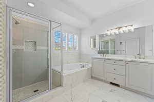 Bathroom featuring a glass-enclosed shower with a recessed niche, a built-in soaking tub with marble-look surround, and a double vanity with light gray cabinetry and white countertops