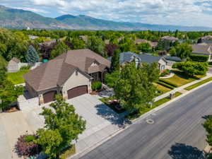 Spacious residence featuring a multi-gabled roof, attached two-car garage, concrete driveway, and mature landscaping