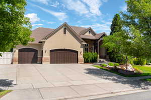 Stucco and stone exterior featuring a multi-gable roofline, two-car garage, and an additional single-car garage
