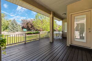 Covered outdoor deck with dark-stained wood flooring