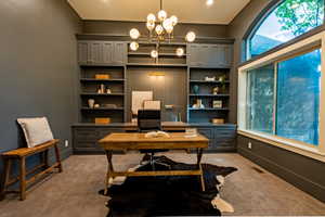 Dedicated office space featuring built-in cabinetry with shelving, a large arched window, recessed lighting, and carpet flooring