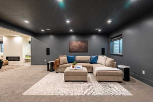 Carpeted entertainment space featuring recessed lighting, a built-in window, and a wide entryway to an additional area with a contemporary fireplace