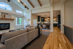 Vaulted living room with exposed wood beams, a white brick fireplace, and an arched window